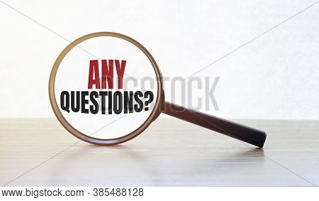 Magnifying Glass With Text Any Questions On Wooden Table.