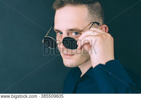 Husband Flirts, Looks Through Glasses. Against A Dark Background.