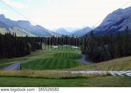 Gorgeous Par 3 On A Golf Course Surrounded By Forest And Big Mountains In The Background, On A Beaut