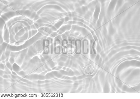 Blurred desaturated transparent clear calm water surface texture with splashes and bubbles. Trendy a