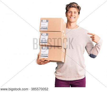 Young handsome man holding delivery package pointing finger to one self smiling happy and proud 