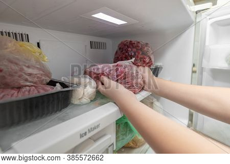 A Woman Puts Frozen Fruit Products In The Freezer, For Long-term Preservation.