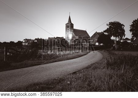 Medieval Church In The Floodplains On A Dike Of A Dutch River Landscape