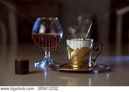 A Glass Of Cognac, A Golden Coffee Cup, A Spoon, Chocolate On The Table, Luxurious Elegance Style Co