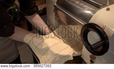 Using Pasta Machine With Dough For Ravioli Making, Male Hands Holding Dough Through Big Past Roller 