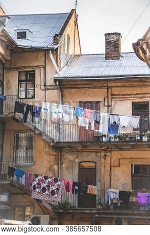 Picture Of Clothes Drying On The Street In Old House. Ancient House With People Living In It And Car