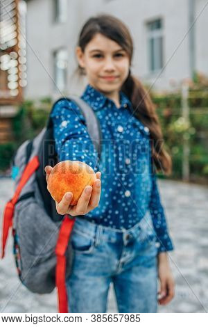 Healthy School Breakfast, Peach In The Hands Of A Schoolgirl.