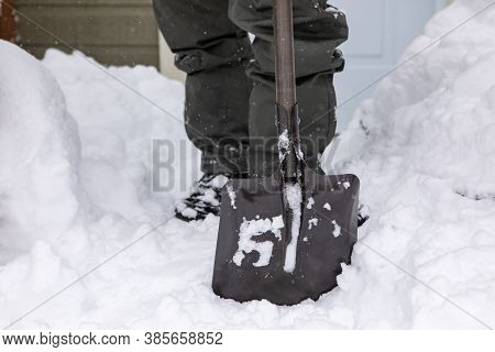 Selective Focus And Close Up On Black Shovel With Square Shaped Blade Held By A Man In Background In