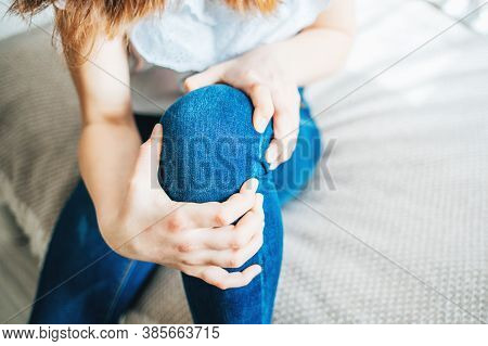Girl Sitting On Bed Clutching A Sore Knee