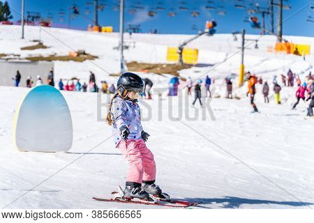 Young Happy Skier Girl Learning How To Ski On The Green Ski Zone. Young Skier Having Fun On Ski Slop
