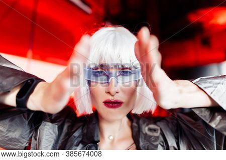 A Woman In A Futuristic Metallic Dress With Glasses Looks Ahead.