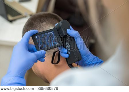 The Doctor Examines The Patient's Scalp Using An Optical Device