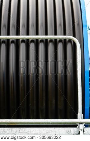 Irrigating With Hose Reel Irrigator. Rolled Up Of Black Rubber Hose, Industrial Detail.