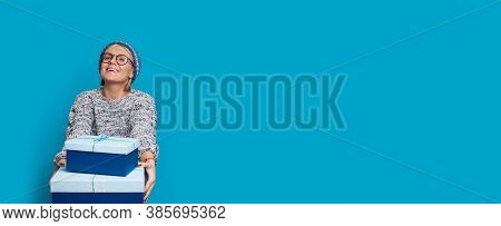 Cute Caucasian Woman Giving Presents At Camera Is Wearing A Hat And Eyeglasses With A Sweater Posing