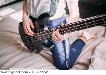 Close Up On The Fingers Of Young Girl Playing Bass Guitar.