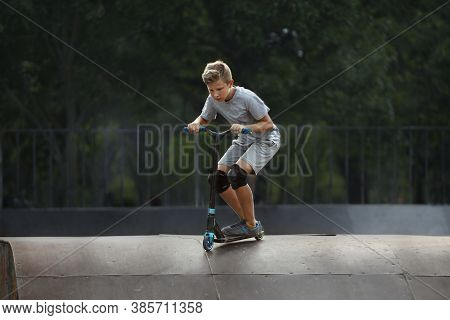 Boy With Scooter Is Going Airborne At A Skate Park.