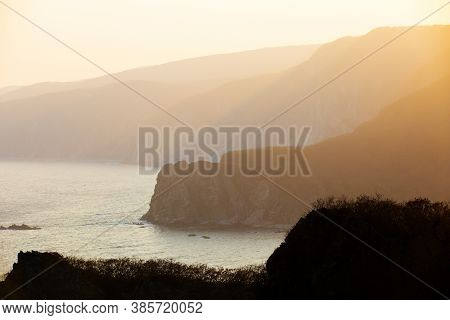 The Rays Of The Setting Sun Make Their Way Through The Rocky Coast Of The Reserve
