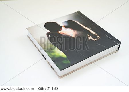 Closed Wedding Photobook With Thick Pages On A White Table. Convenient, Beautiful And Long-lasting S