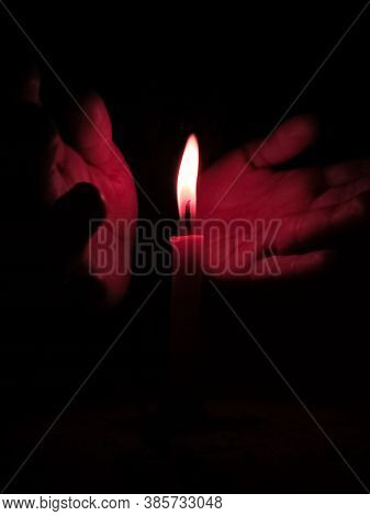 Hands Protecting Flames Of Candle From Air At Night