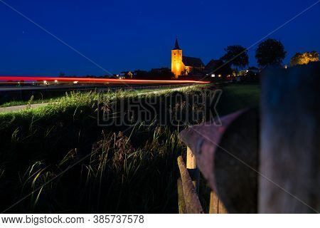 Medieval Church In The Floodplains On A Dike Of A Dutch River Landscape