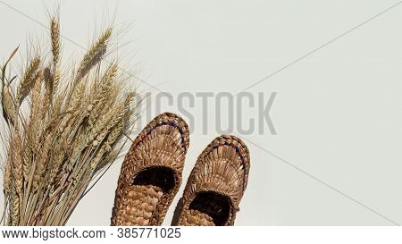 Pair Of Old Bast Shoes And A Sheaf Of Wheat On A Light Background.