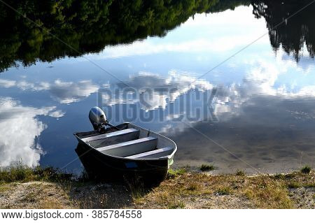 A Small Motor Boat On A Lake Shore
