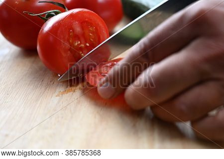 Man Cutting Tomatoes On A Wooden Board