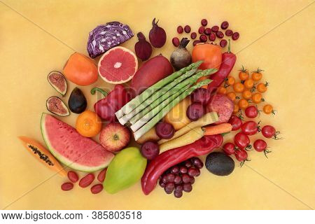 Healthy diet fruit & vegetables high in lycopene for an immune system boost with super foods also high in anthocyanins, antioxidants, vitamins, minerals & dietary fibre. Flat lay on mottled yellow.