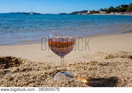 Glass Of Local Rose Wine On White Sandy Beach And Blue Mediterranean Sea On Background, Near Le Lava
