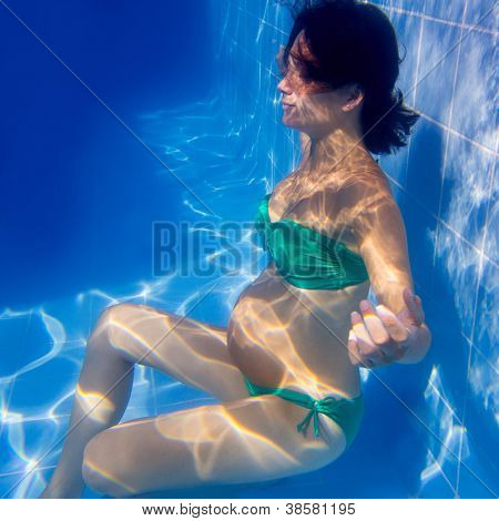Subacquea piscina blu donna incinta bella rilassata