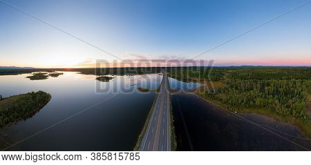 Picturesque Aerial View Of Canadian Scenic Road Surrounded By Peaceful Lakes. Vibrant Summer Sunset 