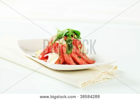 skiva köttet i högen, dekorerad med rucolla och parmesan