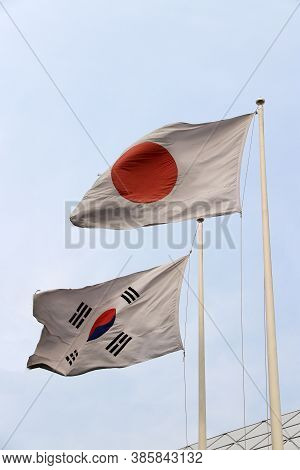 The Flag Of Japan And Republic Of Korea On Blue Sky Background, Red Circle On The White In Japanese 