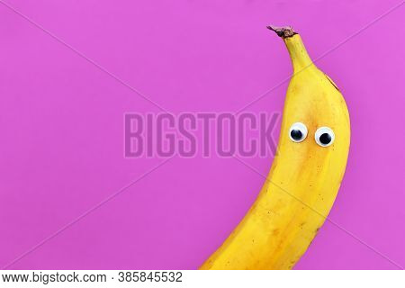 Funny Banana Fruit With Googly Eyes On Purple Background With Blank Copy Space