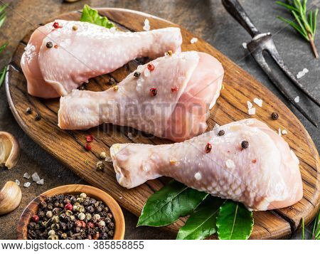 Chicken legs with spices and salt  ready for cooking on cutting board.