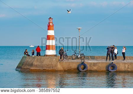 Nida, Lithuania - September 2020: Red And Light Lighthouse In Nida, Lithuania With People, Bikes, Se