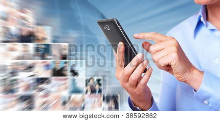 Manos de mujer con un smartphone. Sobre fondo azul.