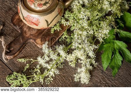 Blooming Meadowsweet Twigs With A Teapot On A Table