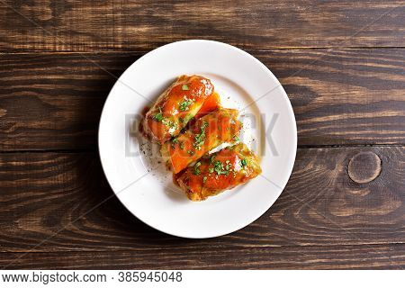 Cabbage Rolls Stuffed With Ground Beef, Rice And Baked With Tomato Sauce On Plate Over Wooden Backgr