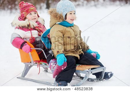 Twee kleine kinderen zitten in de slee in winter park