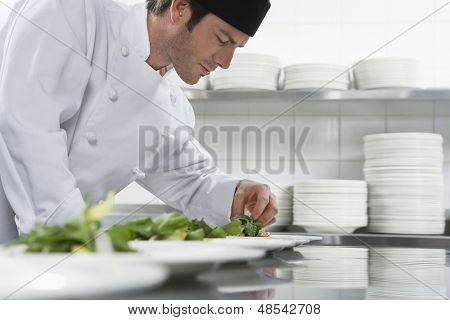 Side view of a male chef preparing salad in kitchen