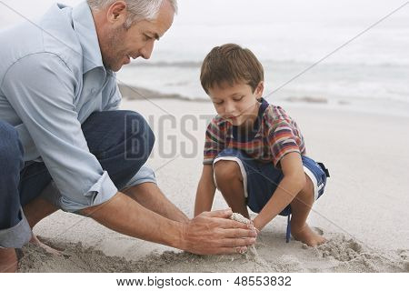 Closeup von Vater und Sohn machen Sandburg zusammen am Strand