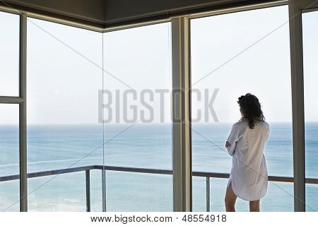 Vista traseira da jovem mulher olhando a vista para o mar da varanda no resort