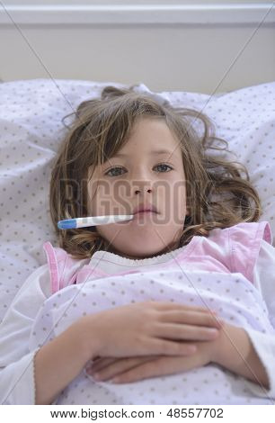 niña enferma descansando en la cama con temperatura de fiebre midiéndolo con termómetro