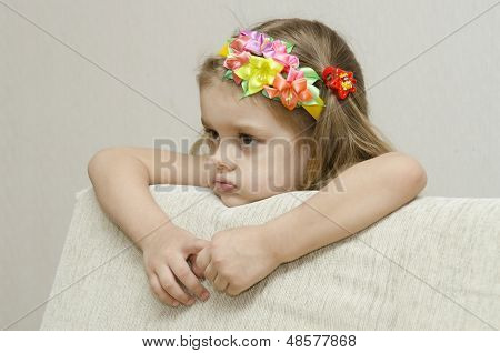 Portrait of a girl that looks thoughtfully left leaning his elbow on the back of the sofa