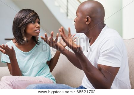 Angry couple having a dispute on sofa at home in the living room