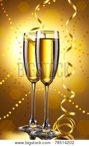 Glasses of champagne with serpentine on bright background