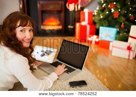 Pretty woman lying on floor using technology at Chritmas at home in the living room