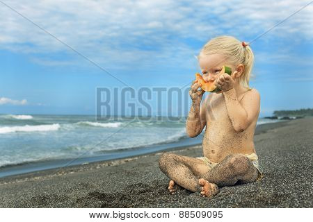 Little Cute Girl On The Sea Beach Eating Ripe Papaya