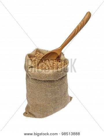 Dry buckwheat and wooden spoon in burlap bag